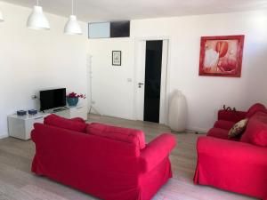 a living room with two red couches and a tv at Sole e Luna in Marina di Modica