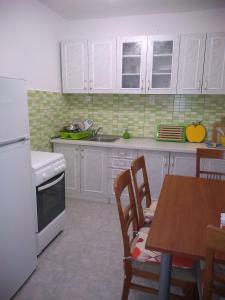 een keuken met witte kasten en een tafel met stoelen bij House Filip in Bogomolje
