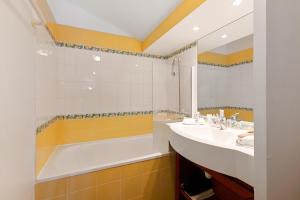 a bathroom with a sink, mirror, and bathtub at Résidence Pierre & Vacances Le Mont Soleil in La Plagne