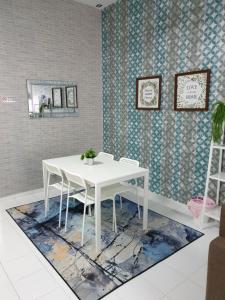 a white dining room table with chairs on a rug at Teratak Mini Pool Homestay Melaka in Melaka