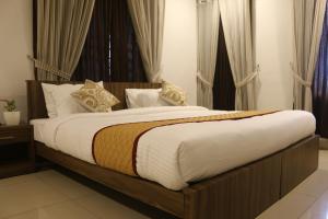 a large bed in a bedroom with curtains at The Rubis in Kottakkal