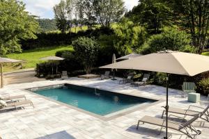einen Pool mit Stühlen und einem Sonnenschirm in der Unterkunft Maison d'hôtes & SPA La Scierie in Salins-les-Bains