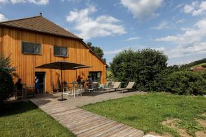 une terrasse en bois avec un parasol à côté d'un bâtiment dans l'établissement Maison d'hôtes & SPA La Scierie, à Salins-les-Bains