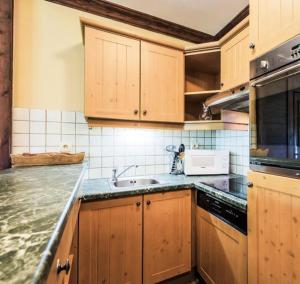 eine Küche mit Holzschränken und einer Arbeitsplatte in der Unterkunft Appartement montagne spacieux, piscine, SPA à ARC 1950 in Arc 1950