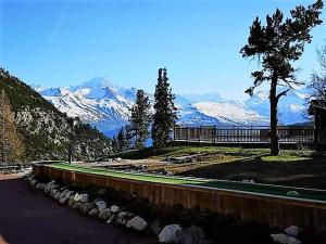 a road with a tree and snow covered mountains at Appartement montagne spacieux, piscine, SPA à ARC 1950 in Arc 1950 +7 photos
