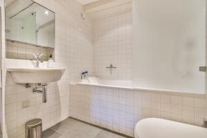 アムステルダムにあるアムステルダム　カナル　ゲスト　アパートメントの白いタイル張りのバスルーム(洗面台、トイレ付)
