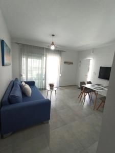uma sala de estar com um sofá azul e uma mesa em Steps to the sea em Néa Péramos