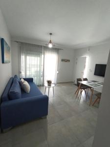 a living room with a blue couch and a table at Steps to the sea in Nea Peramos