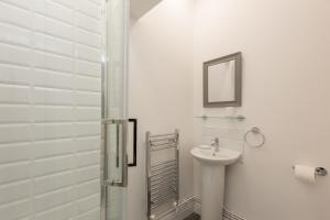 ein weißes Bad mit einem Waschbecken und einer Dusche in der Unterkunft Townhouse PLUS @ 130 West Street Crewe in Crewe