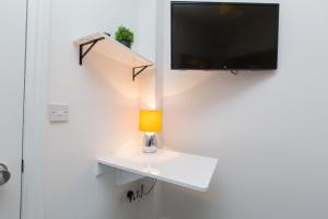 eine Lampe auf einem weißen Tisch mit einem TV an der Wand in der Unterkunft Townhouse PLUS @ 130 West Street Crewe in Crewe
