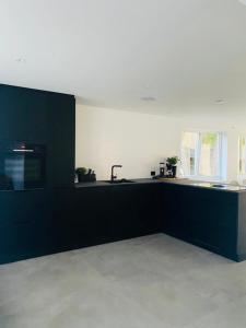 a kitchen with black cabinets and a black counter top at Ferieparadis på sørlandet 2024 in Søgne