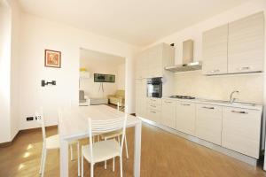 a kitchen with white cabinets and a table and chairs at Casa Costa Outlet 4 in Serravalle Scrivia