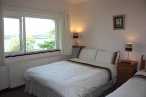 a bedroom with two beds and a large window at Dromcloc House in Bantry