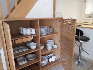 a wooden cabinet with dishes and plates in it at La petite Hautière Maison 2 personnes Plouer sur Rance avec piscine in Plouër-sur-Rance