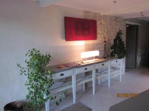 a white desk with a lamp on a wall with plants at A la Maison d'Hôtes in La Baume-de-Transit