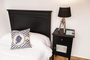 uma cama com uma cabeceira preta e um candeeiro numa mesa de cabeceira em The Old Seaman Bed & Breakfast em Celorio