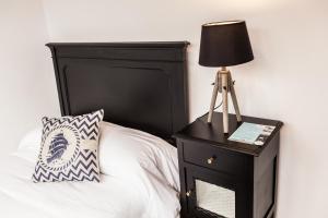 uma cama com uma cabeceira preta e um candeeiro numa mesa de cabeceira em The Old Seaman Bed & Breakfast em Celorio