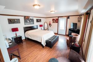 a bedroom with a bed and a couch in it at Auberge du Vieux Faubourg in Sainte-Anne-des-Monts