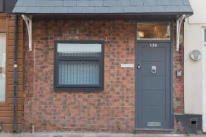 ein Backsteinhaus mit einer schwarzen Tür und einem Fenster in der Unterkunft Townhouse PLUS @ 130 West Street Crewe in Crewe