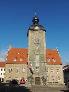 ein großes Backsteingebäude mit einem Uhrturm in der Unterkunft Altstadt Apartments in Querfurt