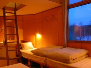 duas camas num quarto com uma escada e uma janela em Kussharo Genya Youth Guesthouse em Teshikaga