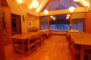 uma sala de jantar com mesas de madeira e uma grande janela em Kussharo Genya Youth Guesthouse em Teshikaga