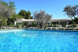 a large pool of blue water in front of a house at Hôtel Villa Glanum et Spa in Saint-Rémy-de-Provence