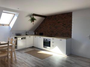 a kitchen with white cabinets and a brick wall at Polne Zacisze in Lgiń +15 photos