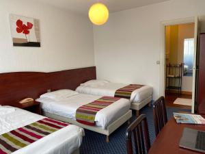 a hotel room with two beds and a table at Hôtel Fontaine, Morlaix in Morlaix +60 photos