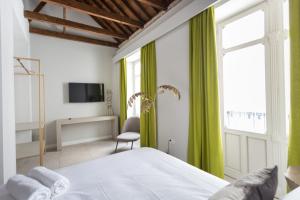 W Thyssen house في مالقة: غرفة نوم بسرير مع ستائر خضراء وتلفزيون