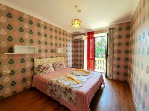 una camera da letto con un letto con una coperta rosa e una finestra di Sunrise Hotel a Kobuleti