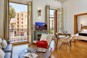 een woonkamer met een bank, een tv en een tafel bij Lodgingmalaga Plaza Constitucion in Málaga