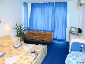 a bedroom with two beds and a couch with blue curtains at Andi Hotel in Chernomorets