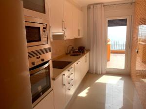 cocina con armarios blancos, fregadero y ventana en Piso 3 dormitorios en Isla del Fraile con terraza y vistas al mar, en Águilas