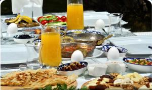 a table topped with plates of food and orange juice at Risus Garden Marina Hotel in Kuşadası