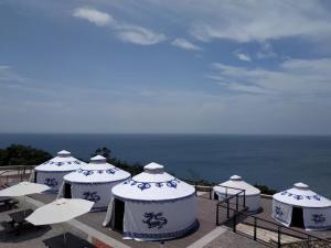 a group of white tents with the ocean in the background at Matsu E19 in Nangan