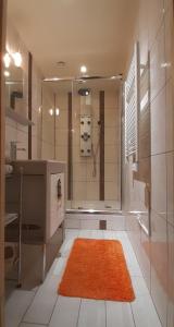 uma casa de banho com um chuveiro e um tapete laranja em La Perle au bord de la rivière em Gérardmer