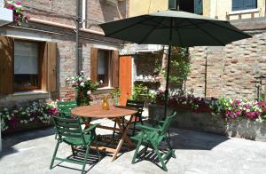 a wooden table with chairs and an umbrella at Ca' Ermina & Garden in Venice