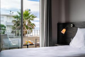 Cette chambre d'hôtel comprend un lit et un balcon. dans l'établissement Hôtel du Midi Plage, à Palavas-les-Flots
