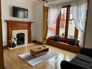 a living room with a fireplace and a tv at Castle Gate Apartment in Jedburgh