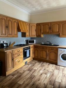 a kitchen with wooden cabinets and wooden floors at Castle Gate Apartment in Jedburgh