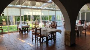 a dining room with tables and chairs and windows at Hotel Restaurant El Bosc in Banyeres del Penedes
