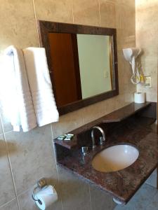 a bathroom with a sink and a mirror and towels at Pousada das Águas in Serra Negra