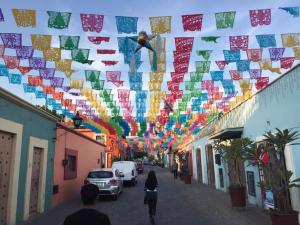 Eine Straße mit bunten Flaggen und Menschen, die eine Straße hinuntergehen in der Unterkunft Los Nardos Hostel -pet friendly- in Oaxaca de Juárez