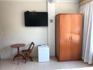 a room with a tv and a chair and a cabinet at Pousada das Águas in Serra Negra