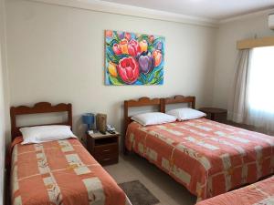 a bedroom with two beds and a painting on the wall at Pousada das Águas in Serra Negra