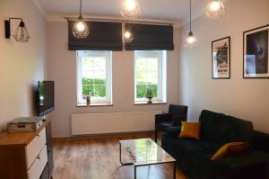 a living room with a green couch and two windows at Apartament Fabryka Endorfin Kłodzko in Kłodzko