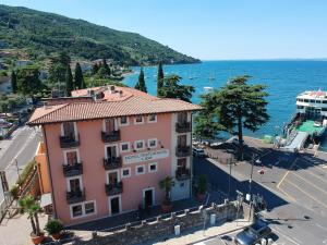 a pink building on a street next to the water at Hotel Lido in Torri del Benaco