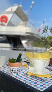 une table avec un tissu de table avec des tasses et une plante dans l'établissement Yacht Le San Lorenzo, au Cap d'Agde