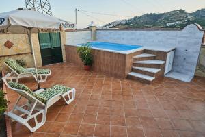 a patio with a swimming pool and chairs and an umbrella at Casa Rural Mi Cortijo in Nerja
